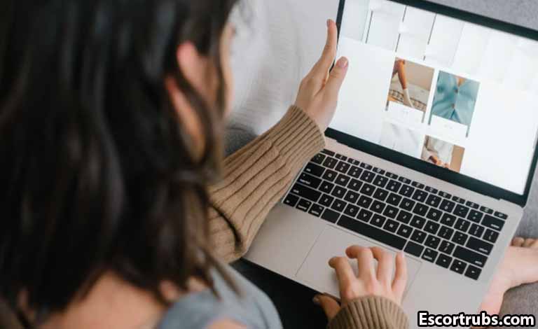 Adult Sex Guide: Building Trust, Respect, and Healthy Adult Bonds Person browses a photo gallery on a silver laptop, left hand resting on the screen and right hand on the keyboard in a cozy setting.